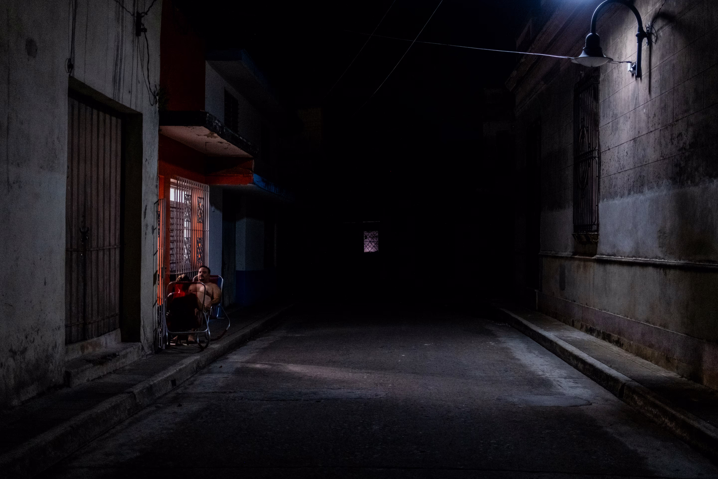 people sit under a light in a darkened street