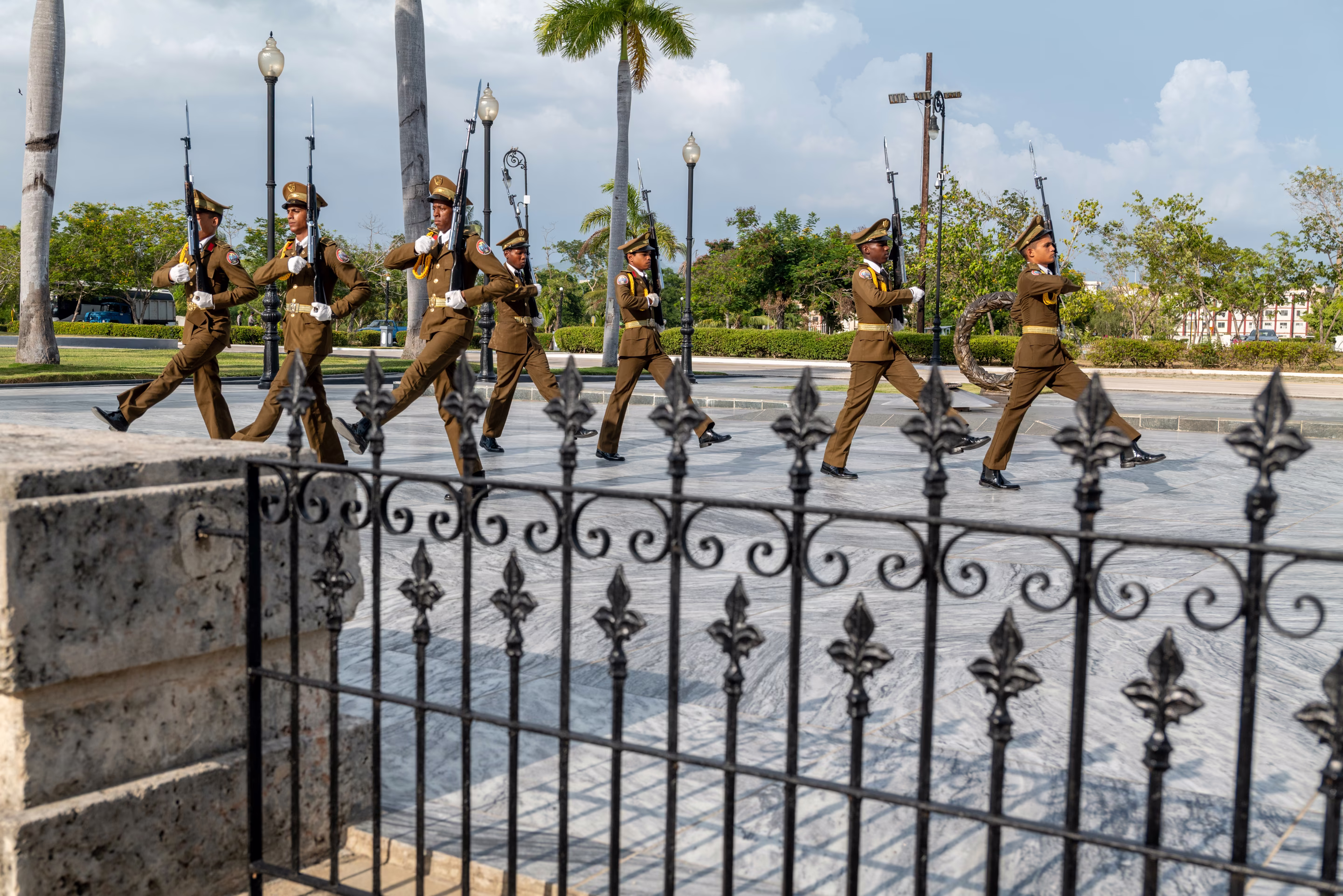 guards march in unison behind an iron gate