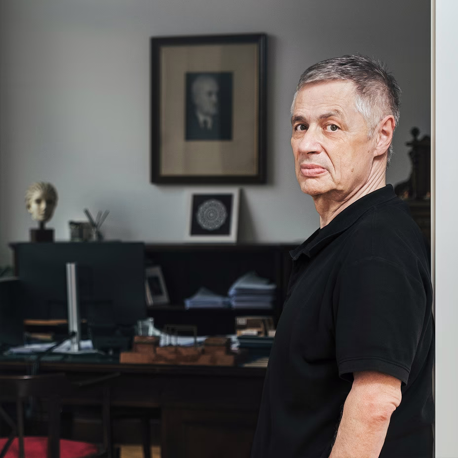 photo of man in black t-shirt with office desk in background