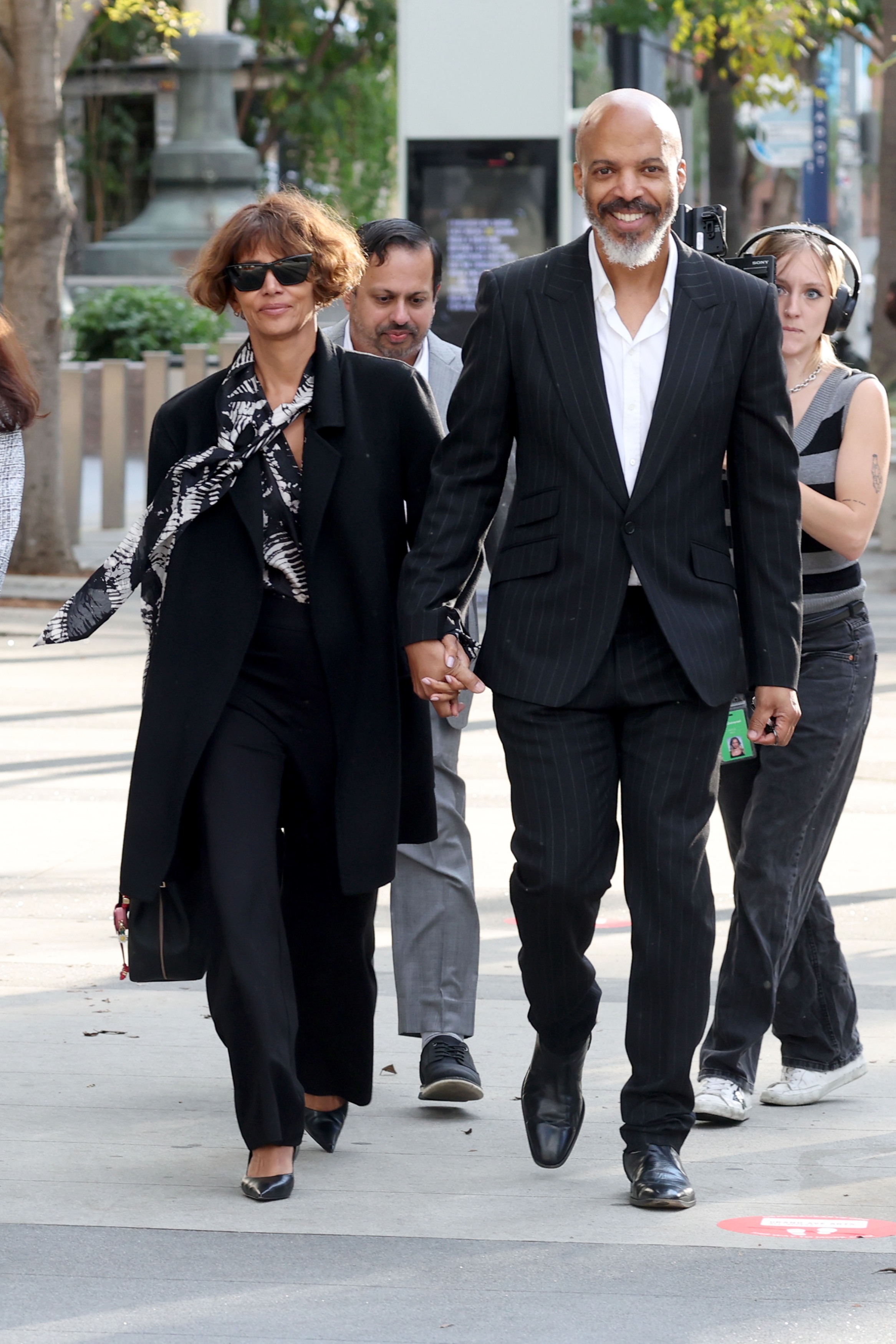 Halle Berry and Van Hunt hold hands while smiling as they walk outside.