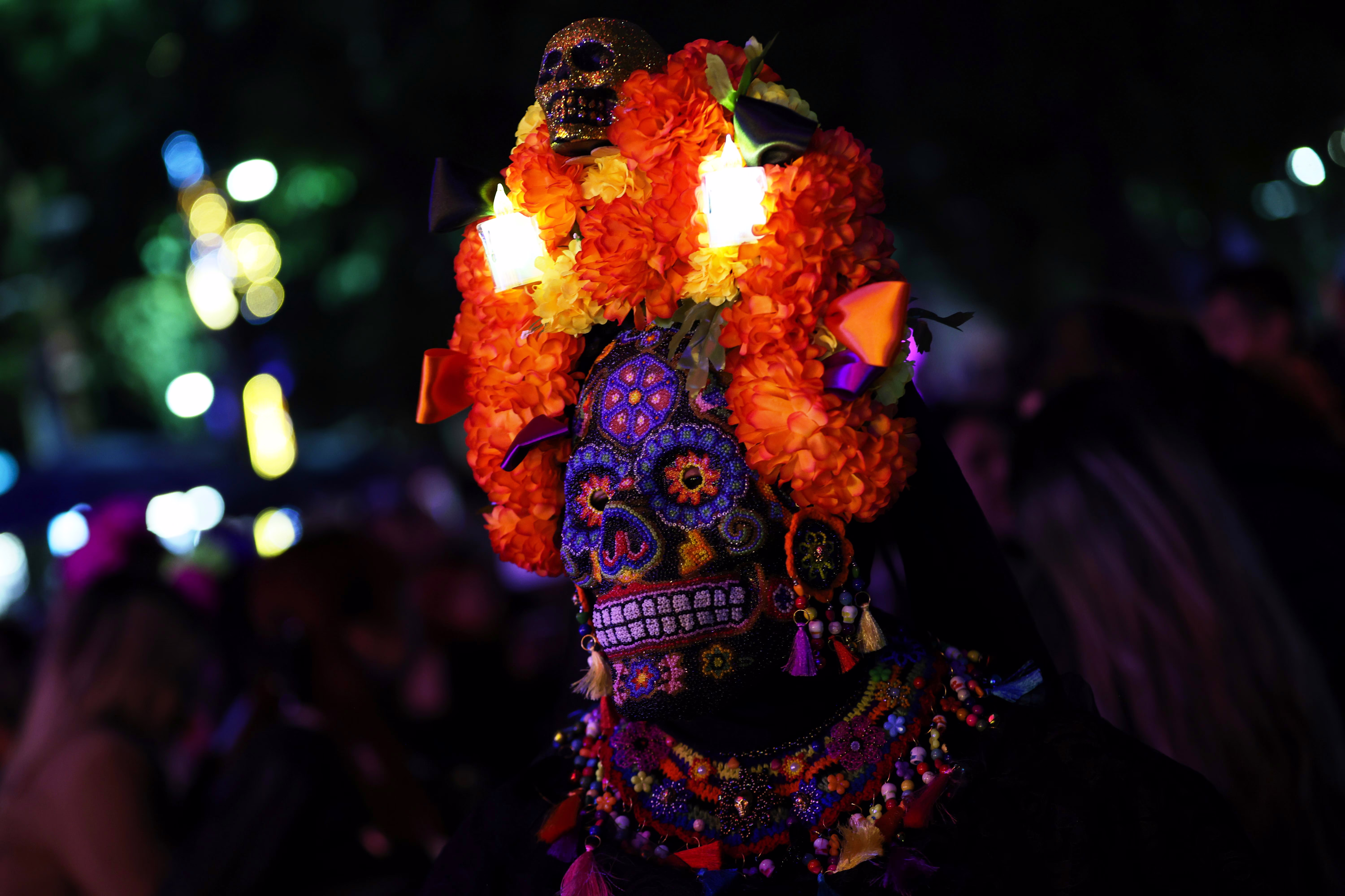 A close view of a person wearing an ornate skull mask with floral headdress