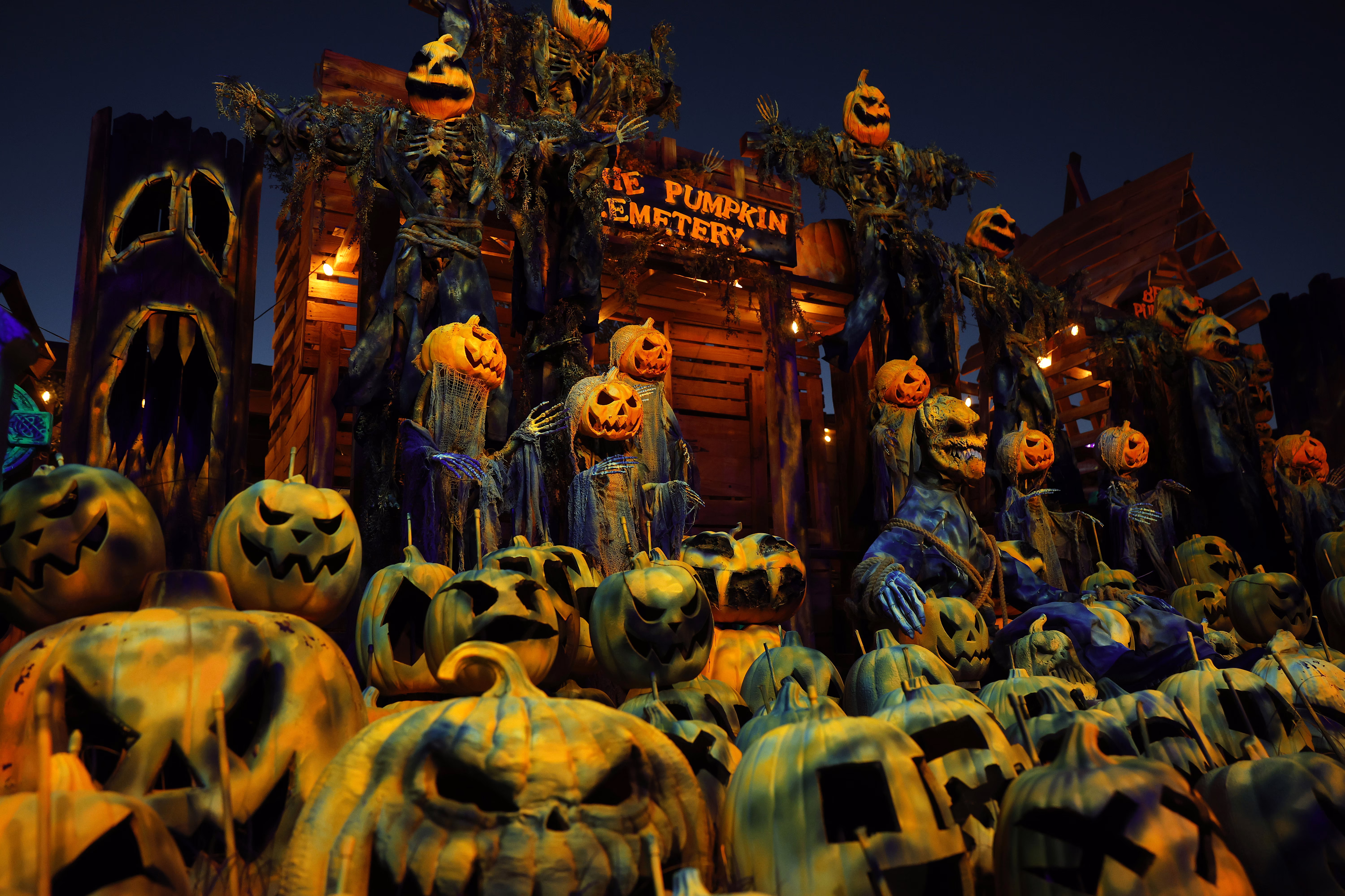 An elaborate Halloween display made up of many scary jack-o'-lantern faces, with a sign that reads 'The Pumpkin Cemetery.'