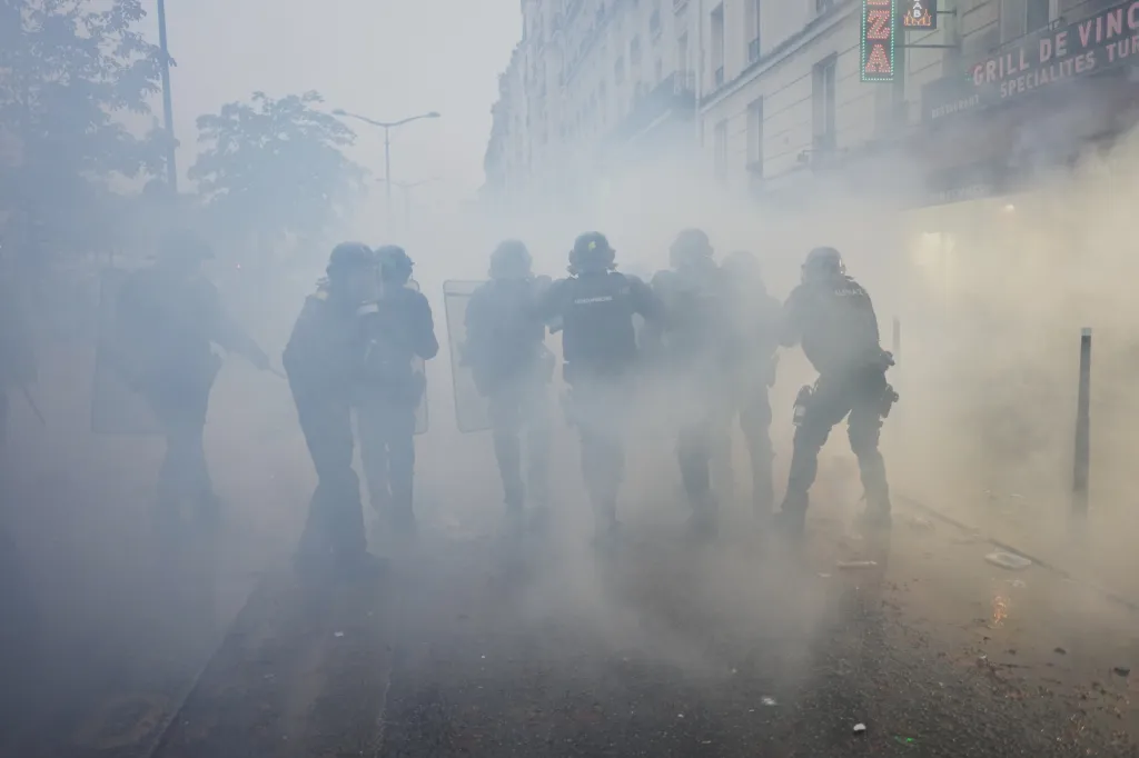 Police officers advance through tear gas during a demonstration in Paris.