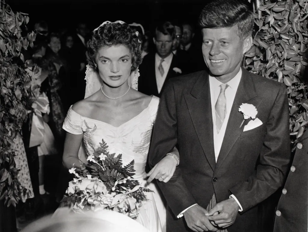 John F. Kennedy and Jacqueline Lee Bouvier walk arm in arm after their wedding.