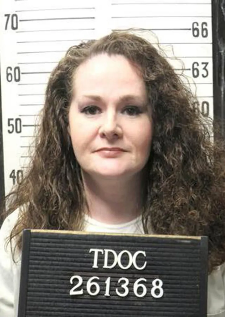 Prison mugshot of Christa Pike in front of a height chart holding a sign with her inmate ID.