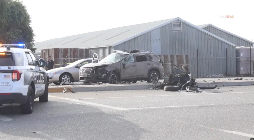Severe damage to multiple vehicles involved in a crash, with a police car parked nearby.