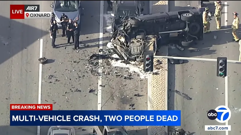 Aerial view of a severe multi-vehicle crash in Oxnard, showing a heavily damaged, overturned vehicle and wreckage strewn across the roadway with emergency responders nearby.