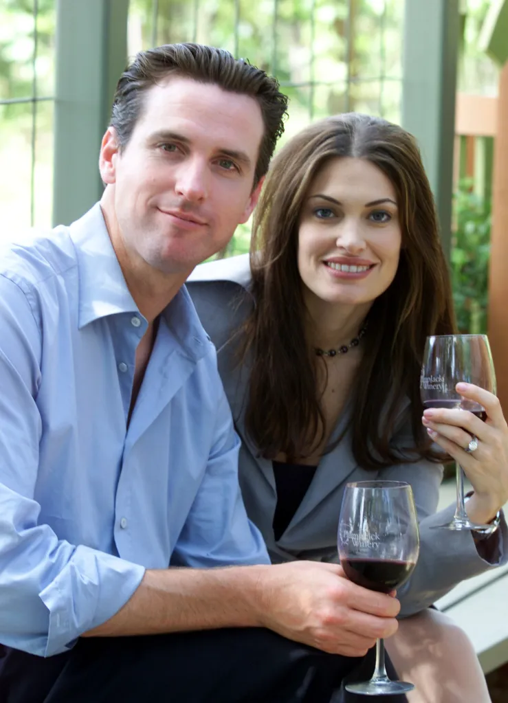 Gavin Newsom and Kimberly Guilfoyle Newsom pose with wine glasses.