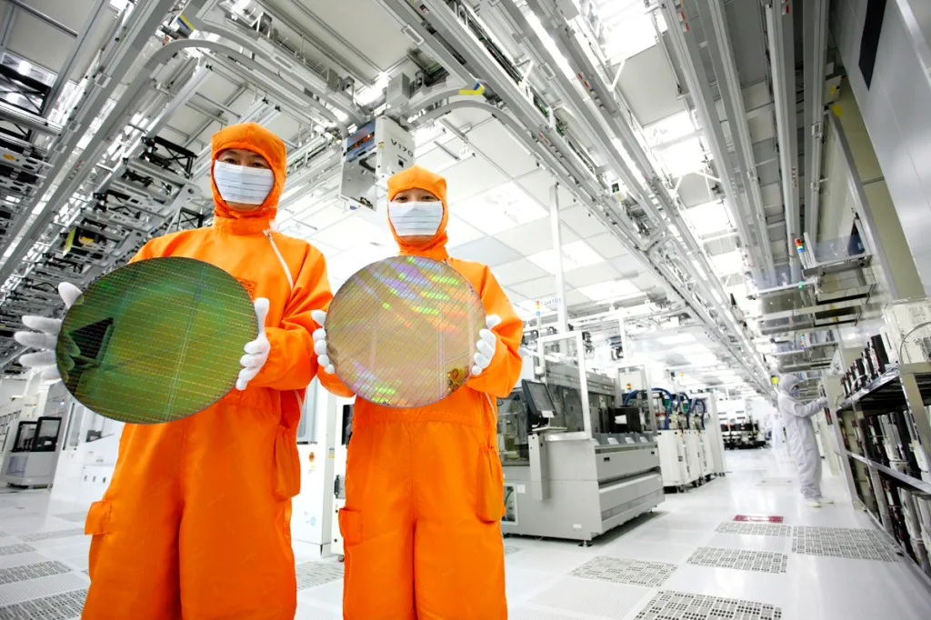 Workers of Hynix Semiconductor pose in cleanroom suits holding semiconductor wafers at a plant in Icheon, South Korea.