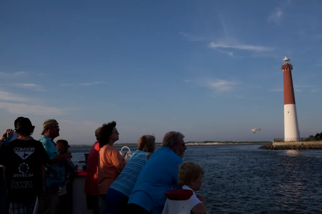 Visitors on the Miss Barnegat Light sunset cruise sail past the Barnegat Lighthouse on the northern tip of Long Beach Island.