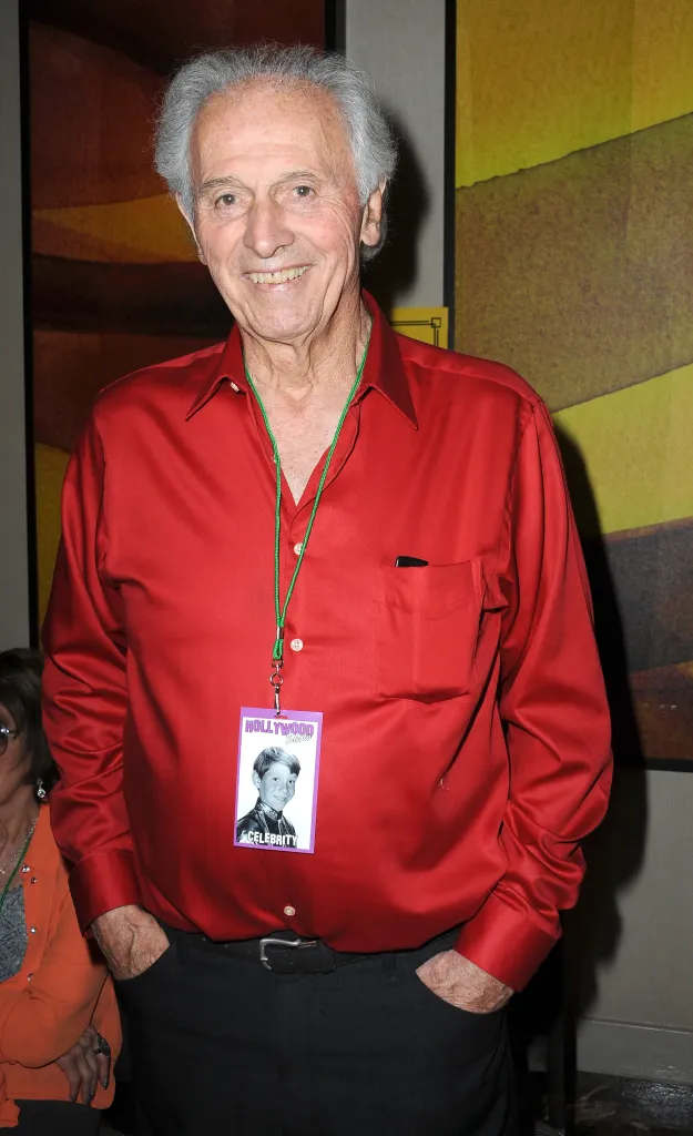 Actor Michael Forest smiling in a red shirt and lanyard with a name tag.