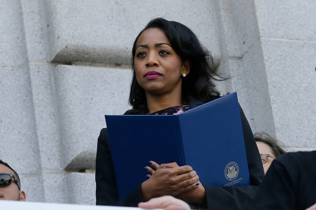 Malia Cohen holding a blue folder.
