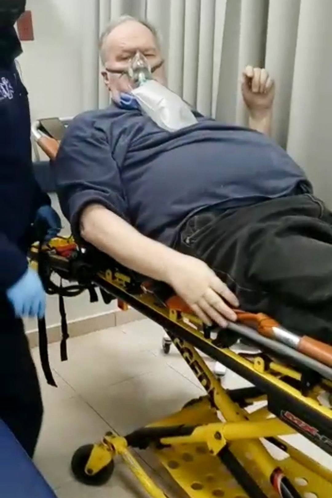 Thomas Markle on a gurney with an oxygen mask.