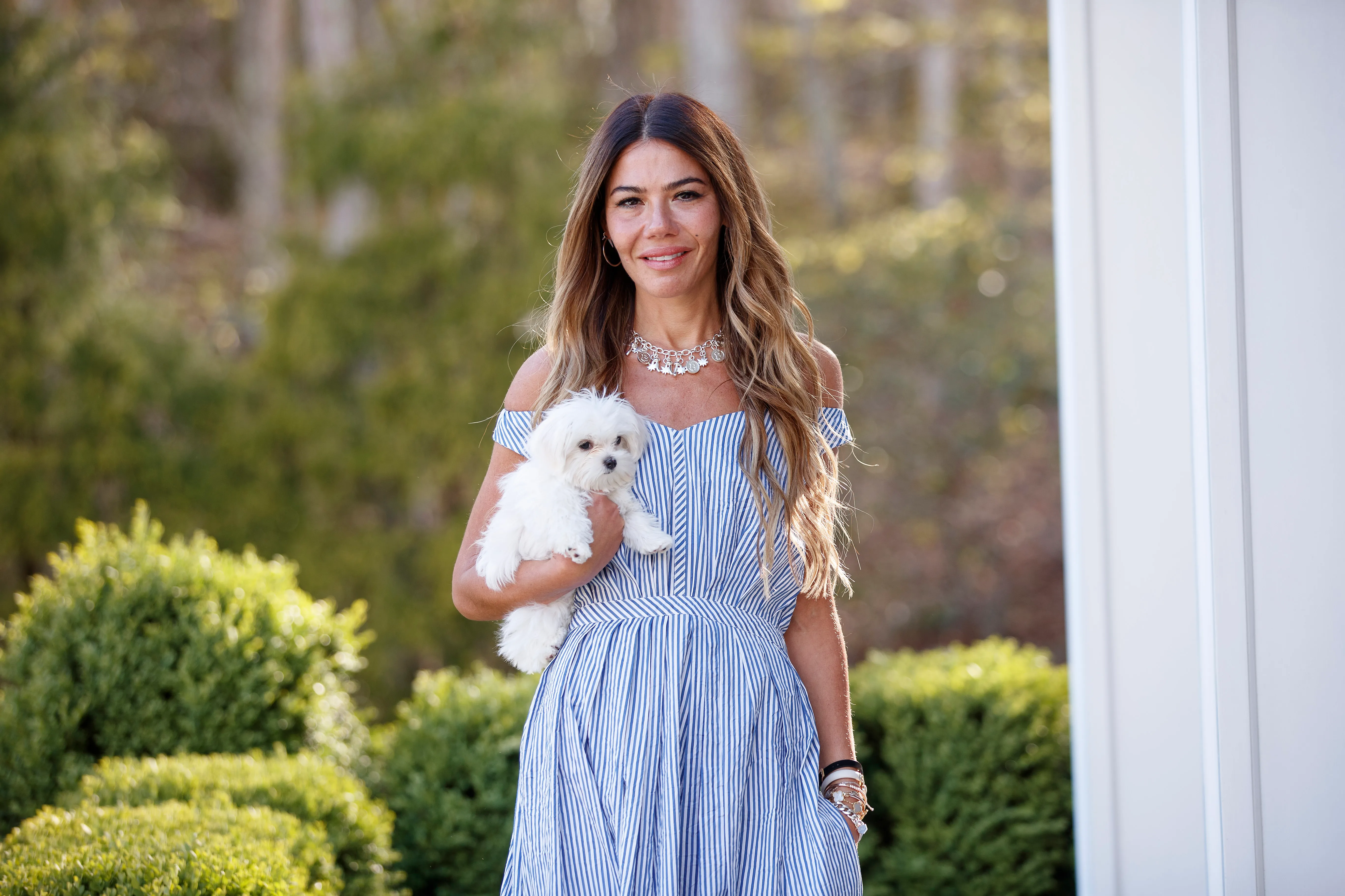 Libbie Mugrabi holding a small white dog outside her Watermill home.