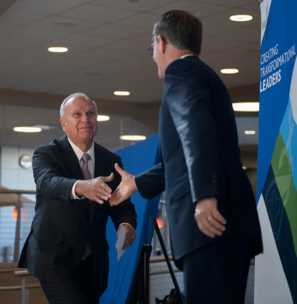 NEOMED President John Langell shakes hands with a man indoors.