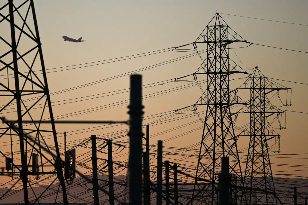 An aircraft takes off at sunset behind electric power lines in El Segundo, California.
