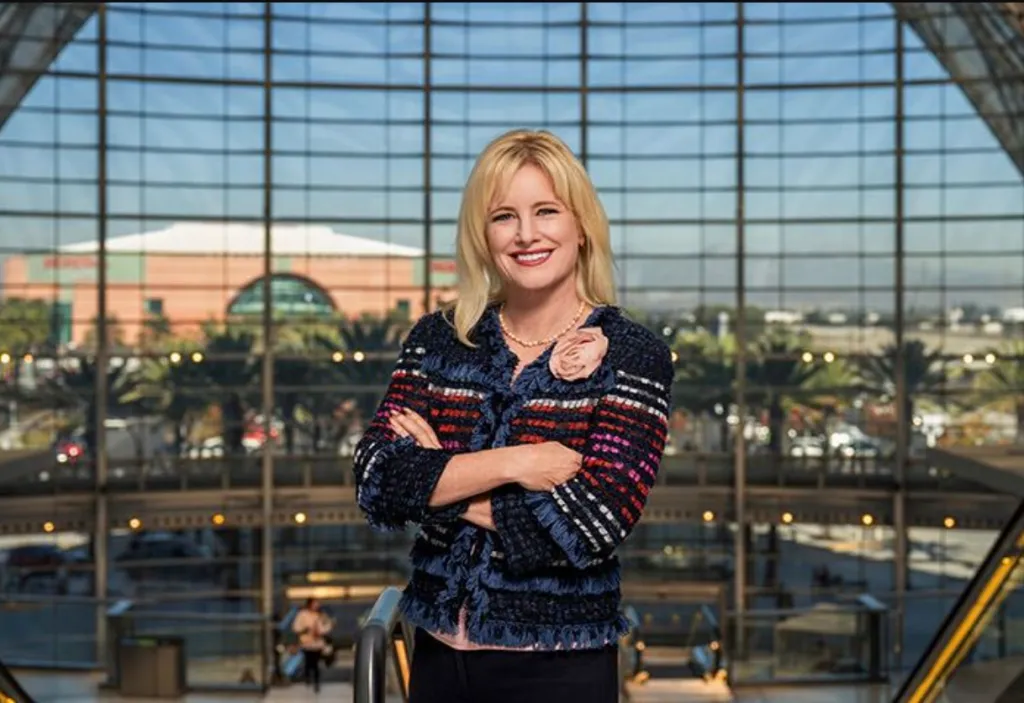 Anaheim Mayor Ashleigh Aitken stands with her arms crossed in front of a large glass window.