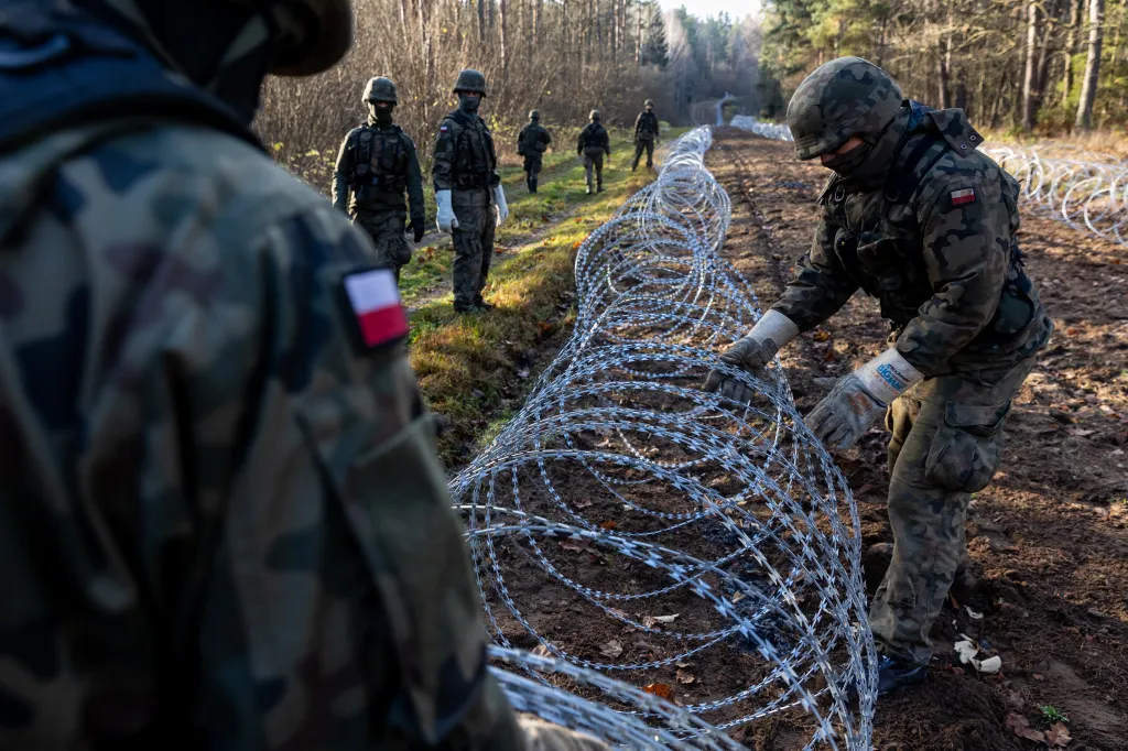 Polish soldiers installing concertina wire along a border.