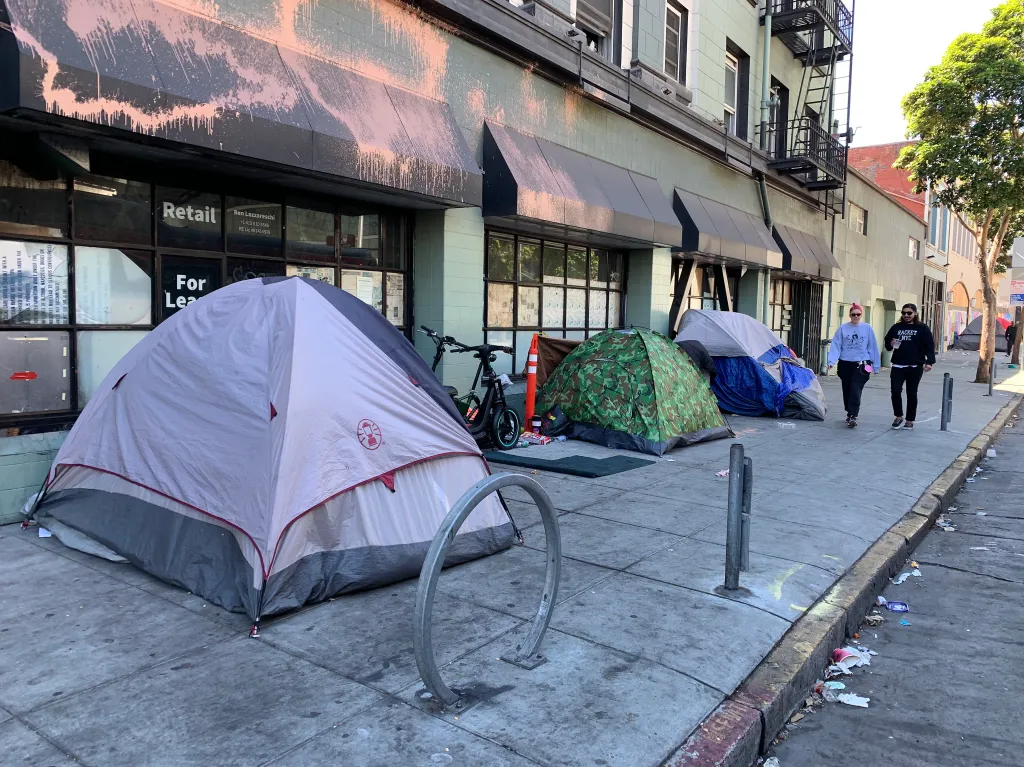 Homeless tents on the sidewalk in front of a commercial building.