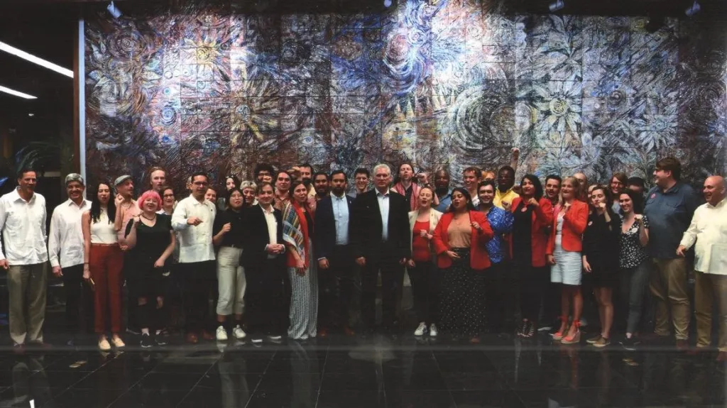 DSA national co-chair Ashik Siddique and a delegation pose for a group photo in front of a large mural.