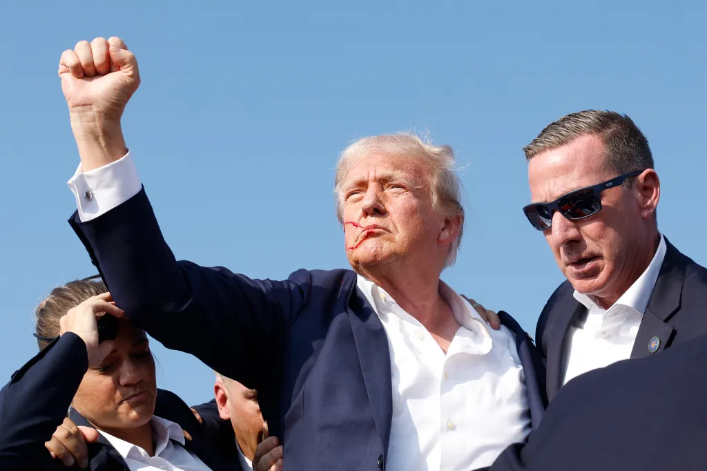 Former President Donald Trump is rushed offstage by Secret Service agents, raising his fist with blood on his face after being injured at a campaign rally.