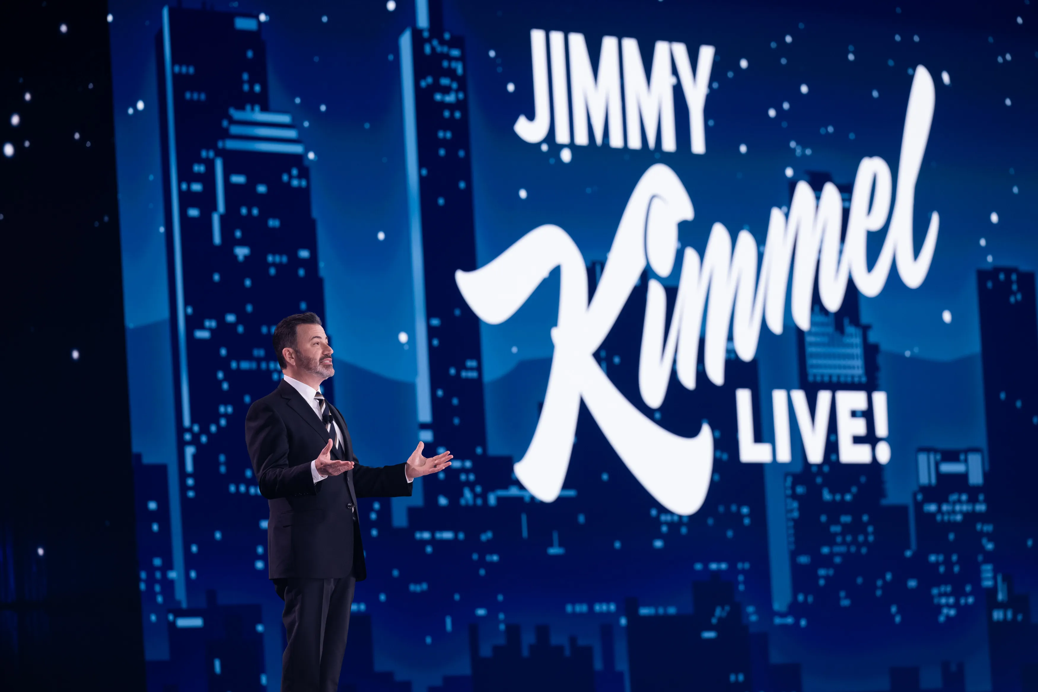 Jimmy Kimmel speaks on stage in front of a 