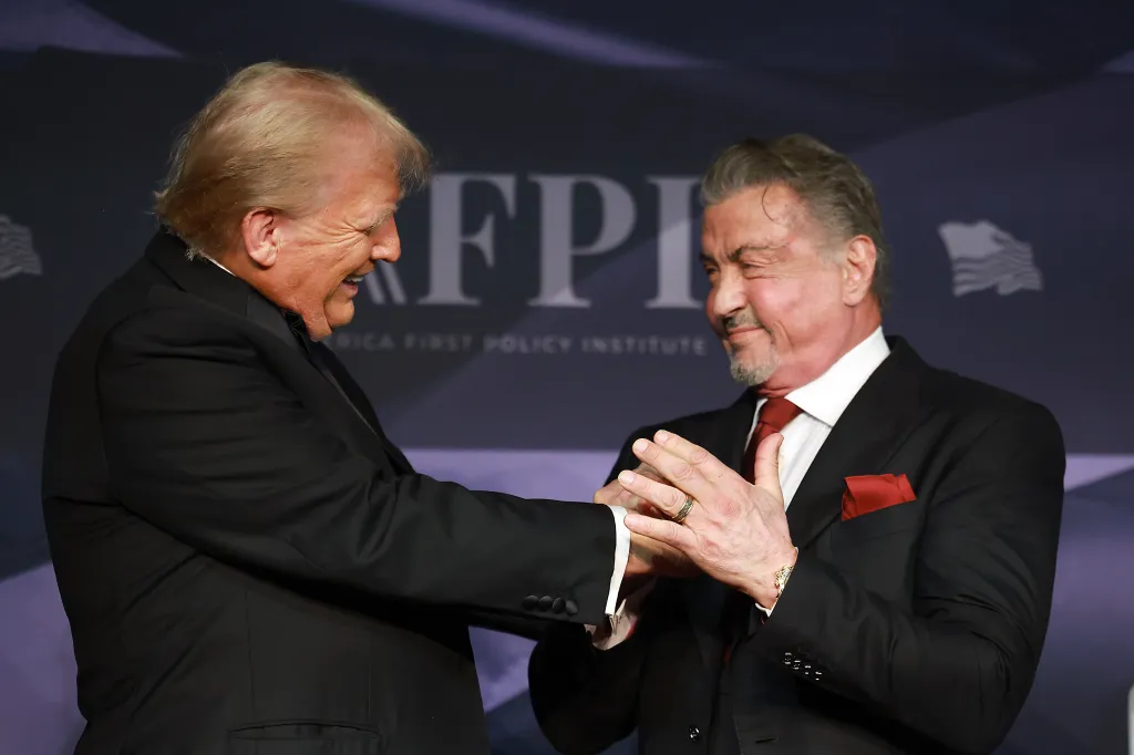 U.S. President-elect Donald Trump greets actor Sylvester Stallone onstage at the America First Policy Institute Gala.