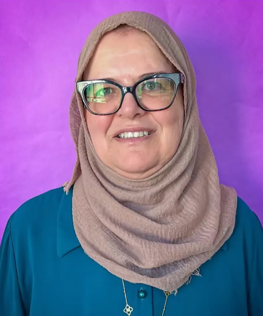 Maysa Jarara wearing a hijab and glasses in front of a purple background.