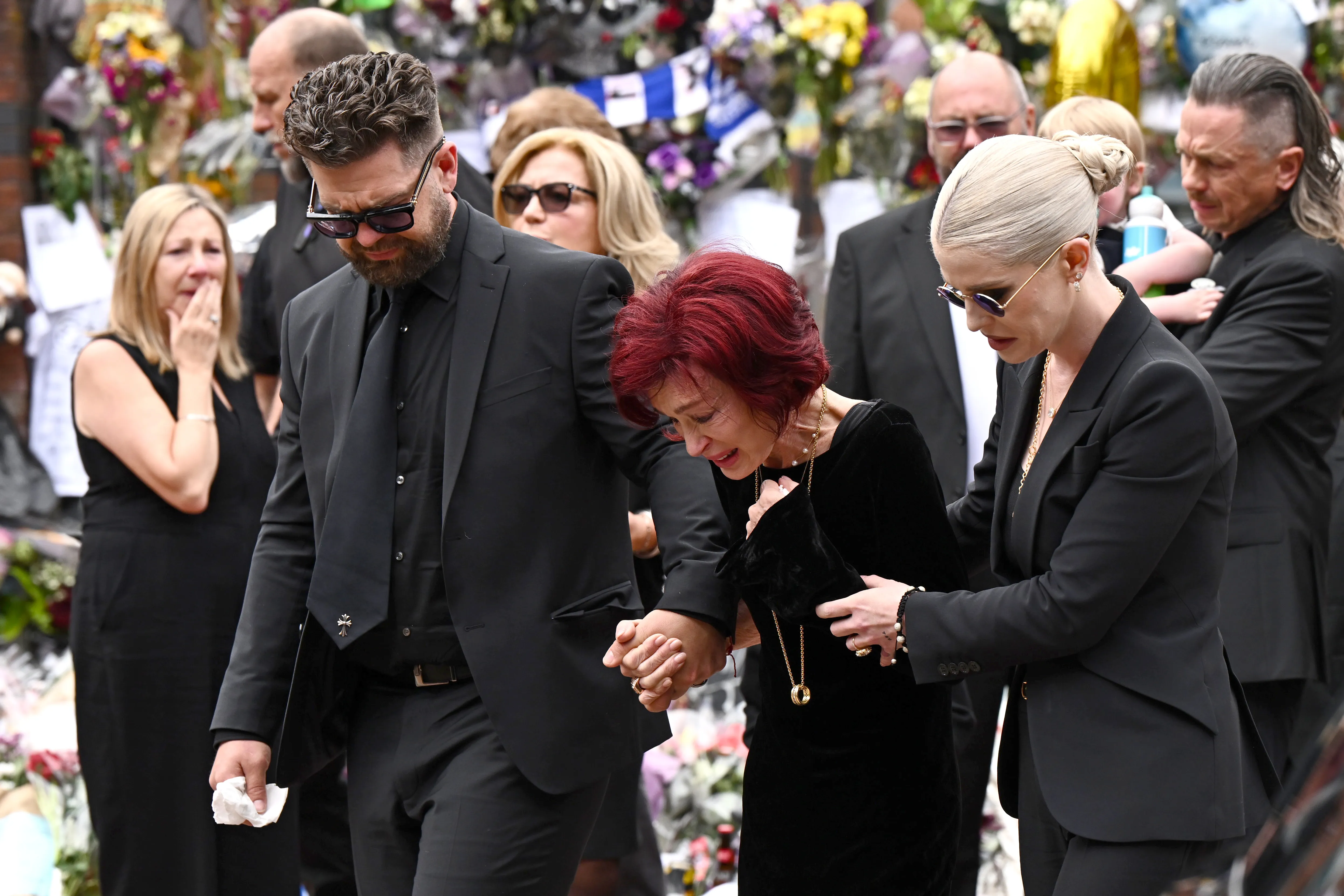 Jack, Sharon and Kelly Osbourne arrive at a makeshift memorial for Ozzy Osbourne during his funeral procession in Birmingham, Britain, on July 30, 2025.