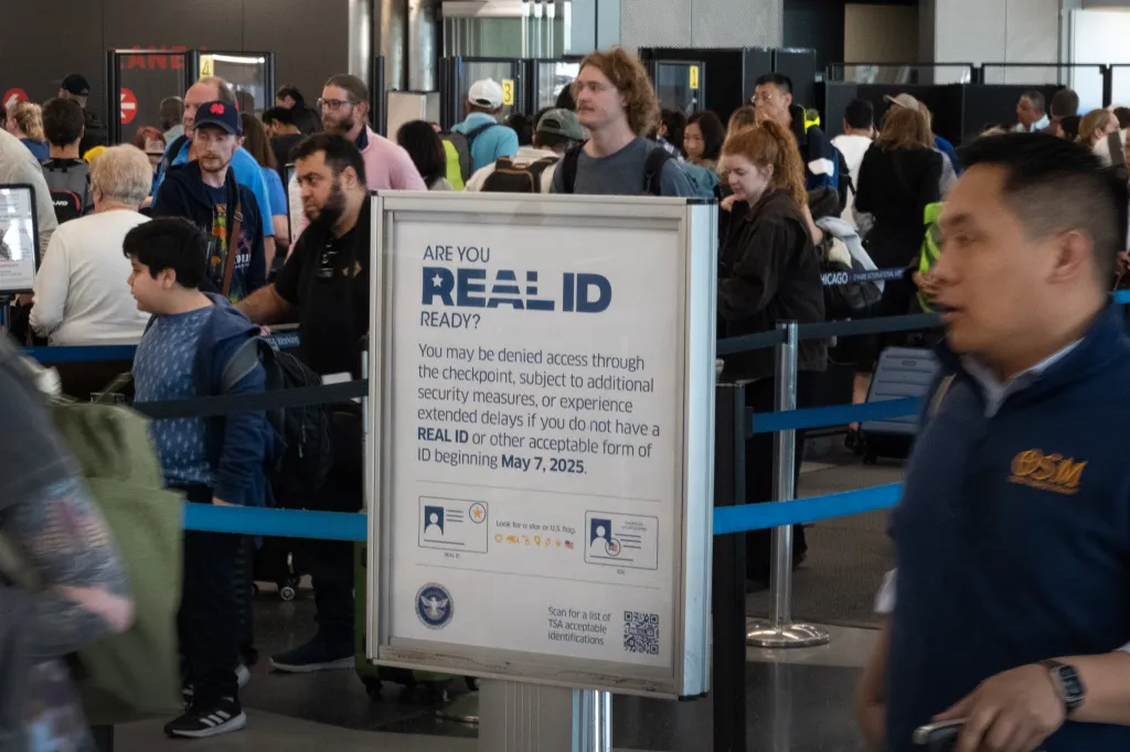 Passengers go through a security checkpoint next to a Real ID informational sign at O'Hare International Airport.
