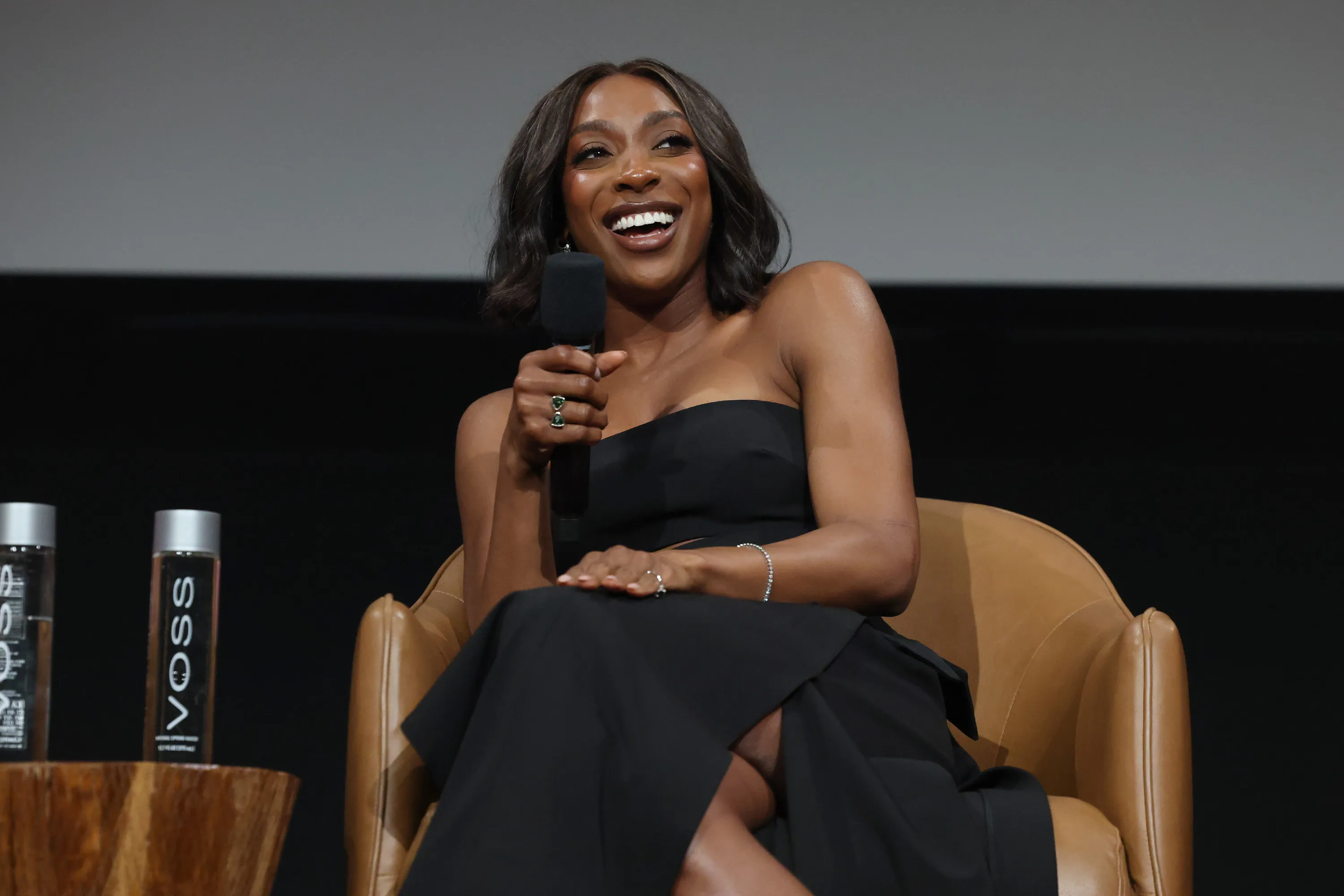 Ego Nwodim speaks into a microphone while seated on stage at a Saturday Night Live FYC event.