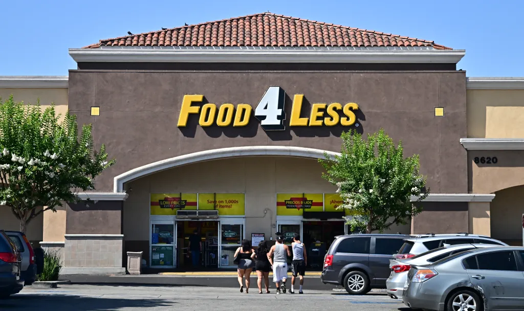 People approach the entrance of a Food4Less grocery store where Immigration and Customs Enforcement agents conducted raids.