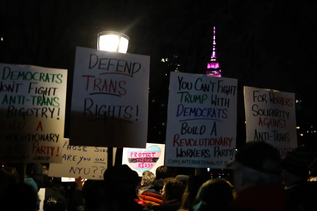 Protestors hold signs defending trans rights in New York City.