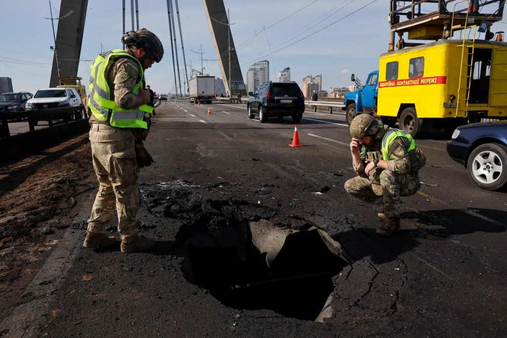 Police officers inspect a large crater caused by a drone strike on the Northern Bridge in Kyiv.