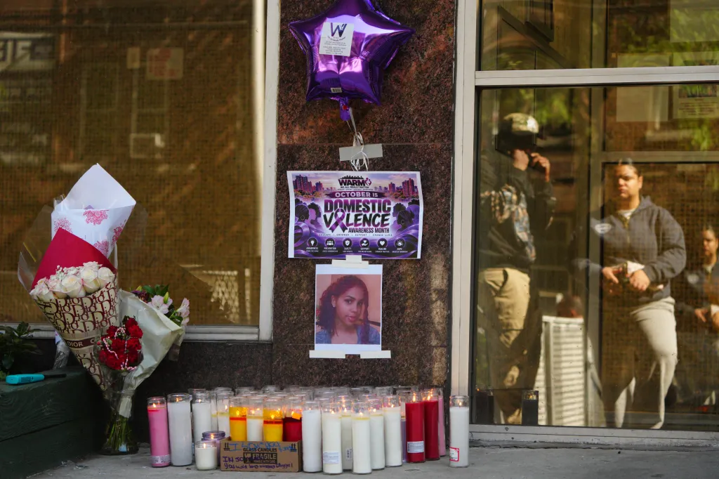 A memorial for Nathaly Ramirez with flowers, candles, a framed photograph, and a poster outside a building.