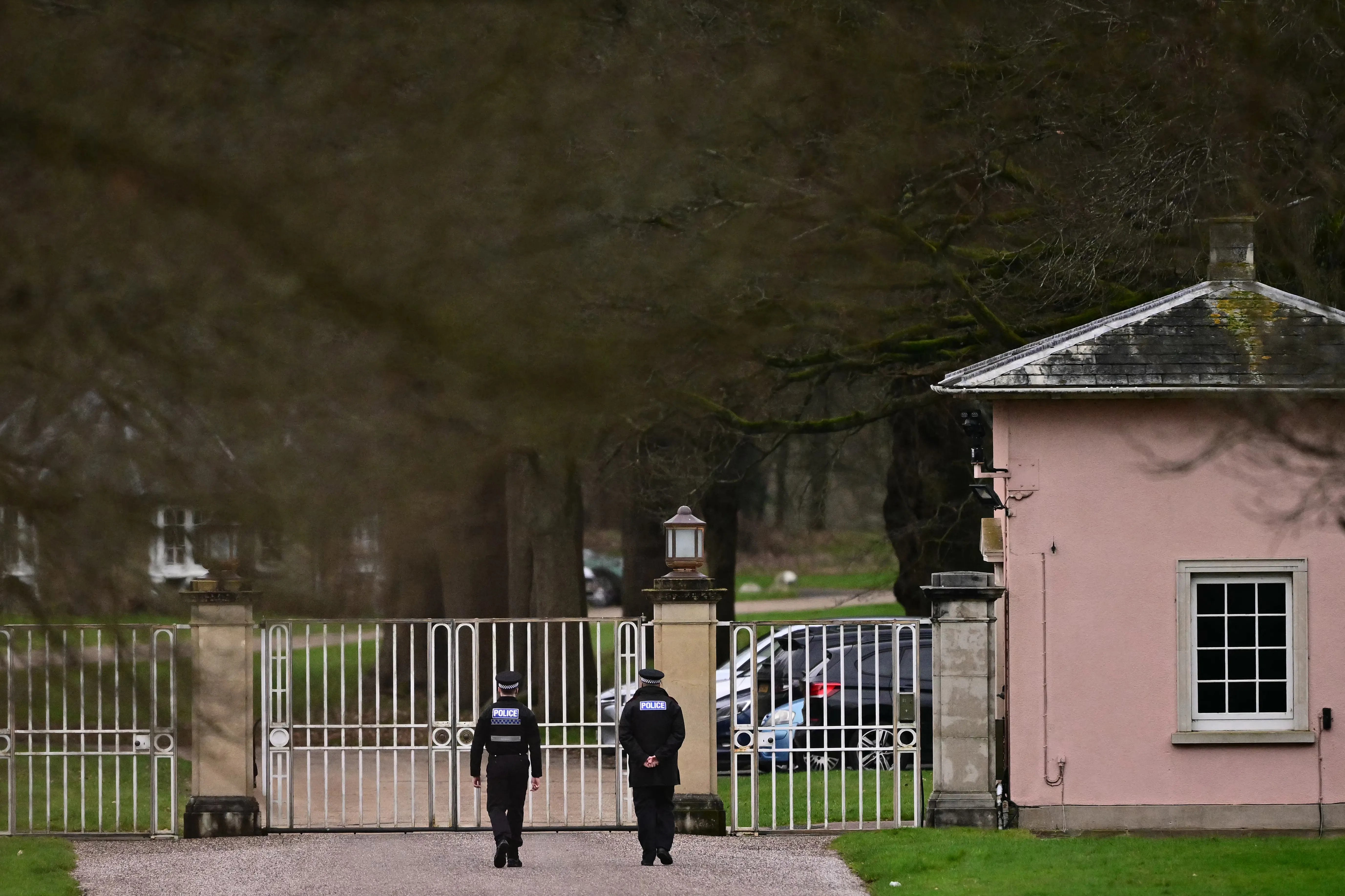 Police officers walk toward the entrance to Royal Lodge, a property belonging to Britain's former prince Andrew.