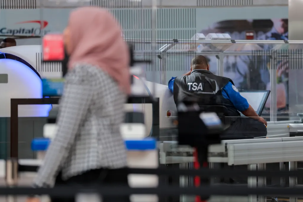 A traveler walks past a TSA agent at a security checkpoint at Dulles International Airport.
