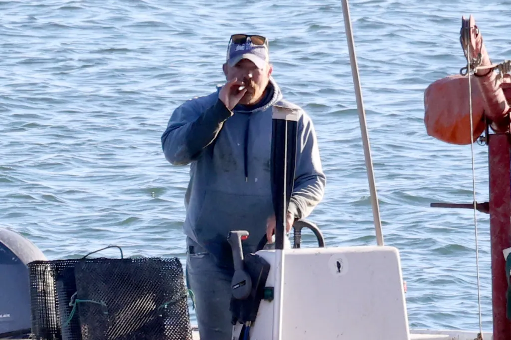 Graham Platner smokes on his boat after oyster fishing in Sullivan, Maine.
