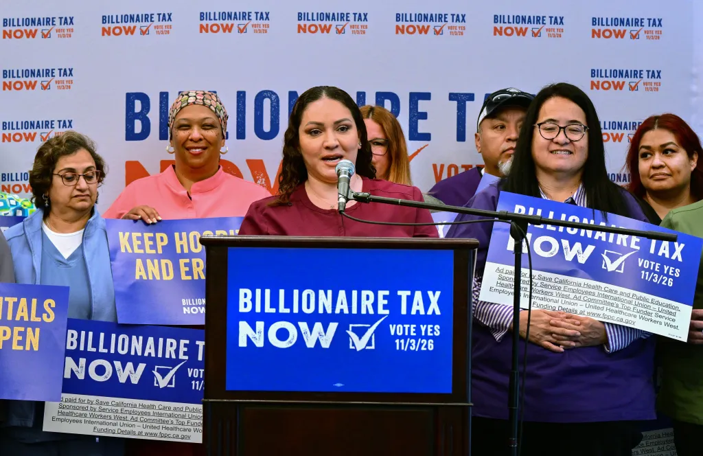 Ultrasound Technologist Mayra Castaneda speaks at a media briefing in front of healthcare workers holding Billionaire Tax placards.