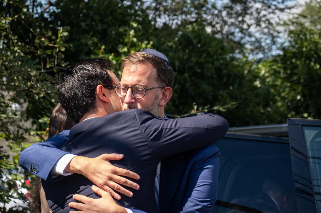 Matthew Rahmani embraces a mourner following his wife's funeral.