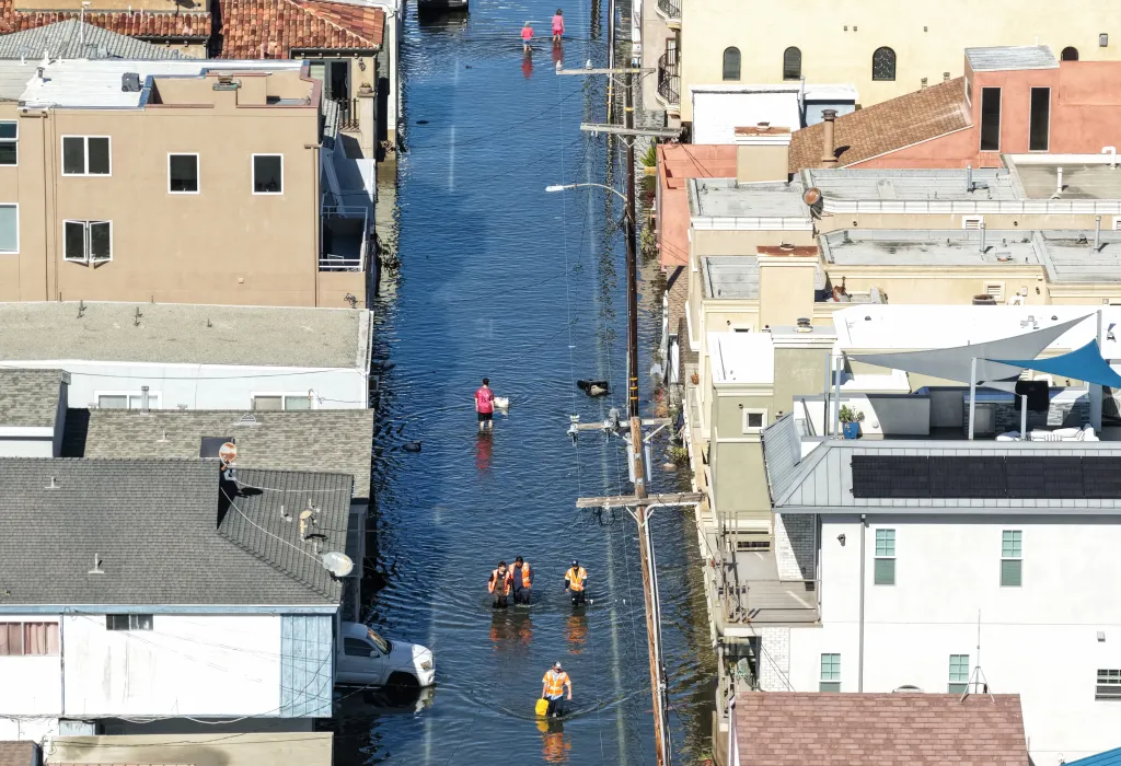 An aerial view shows workers and residents walking through floodwaters in Sunset Beach, California.