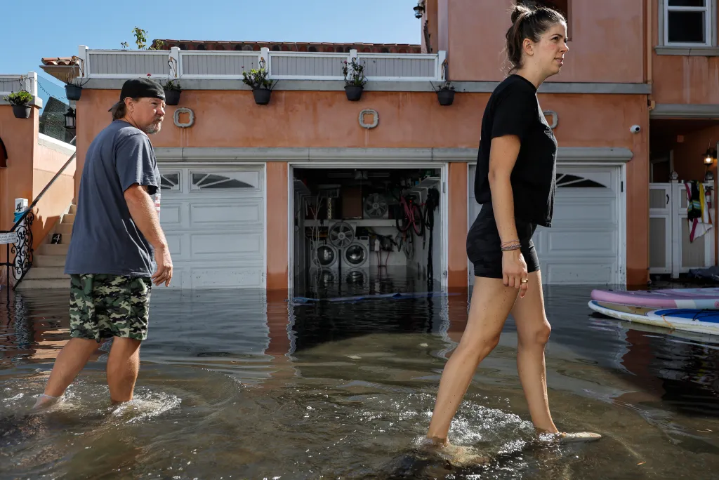 Dani Wynne wades through coastal floodwaters outside her residence during high tide in Huntington Beach, California.