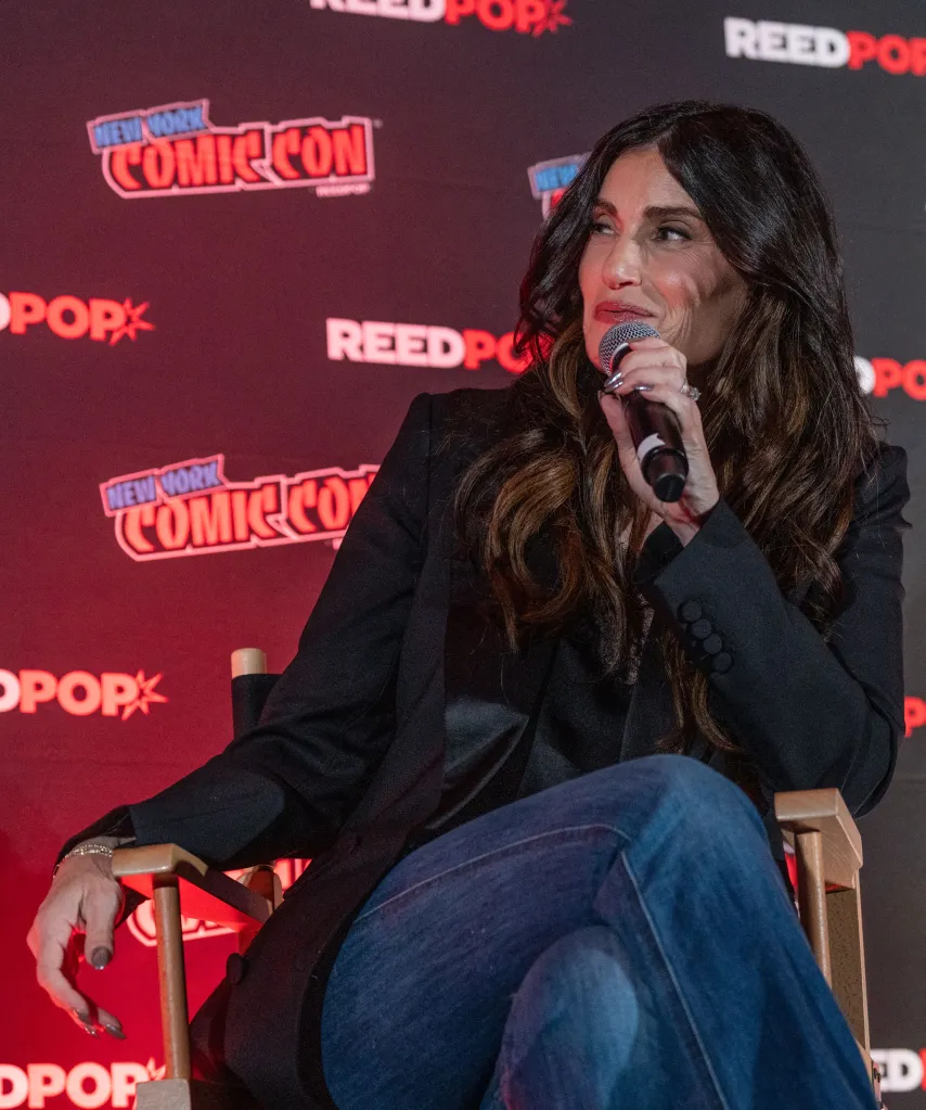 Idina Menzel speaks into a microphone at a panel during New York Comic Con.