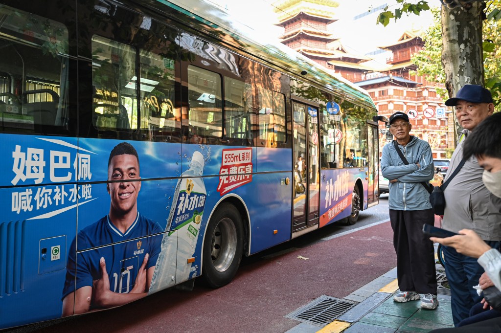 A bus featuring an advertisement of French football star Kylian Mbappe for Dongpeng Beverage Group's 