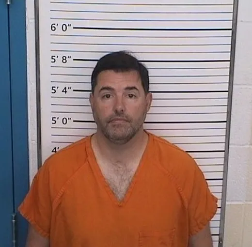 Police booking photo of San Francisco 49ers owner Jed York in an orange jumpsuit against a height chart.
