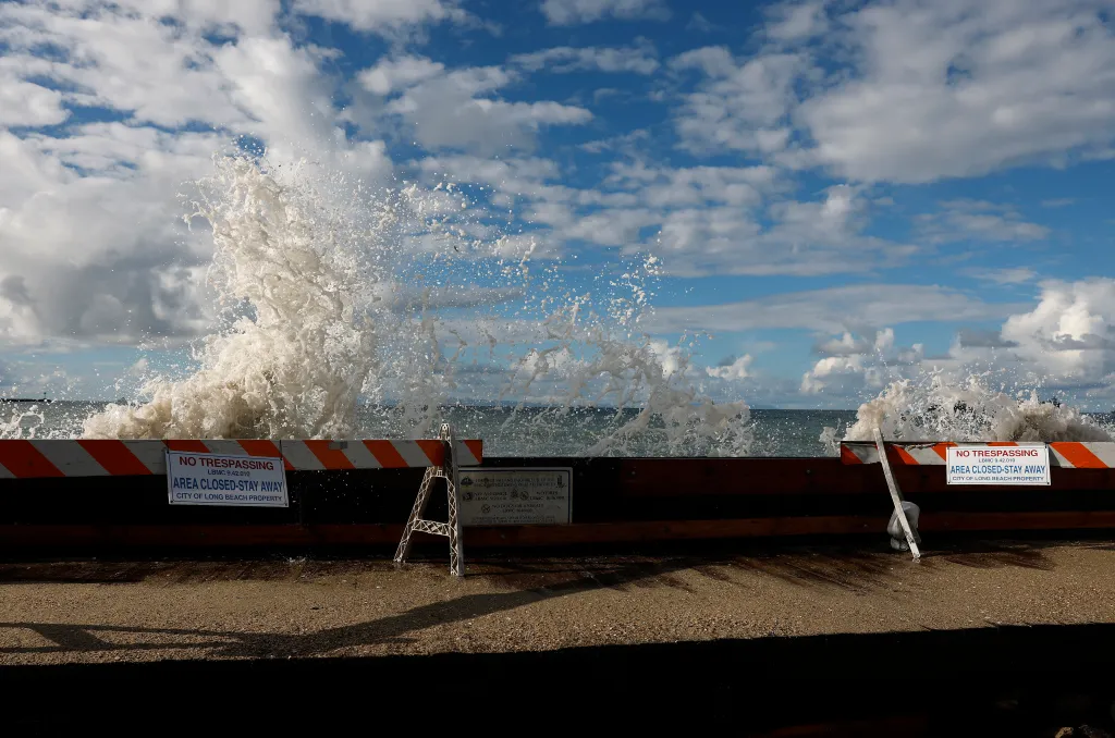 Waves crash over a seawall behind a 