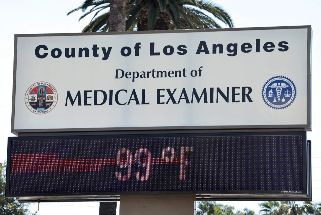 An outdoor digital sign outside the County of Los Angeles Medical Examiner displays a temperature of 99 degrees Fahrenheit.