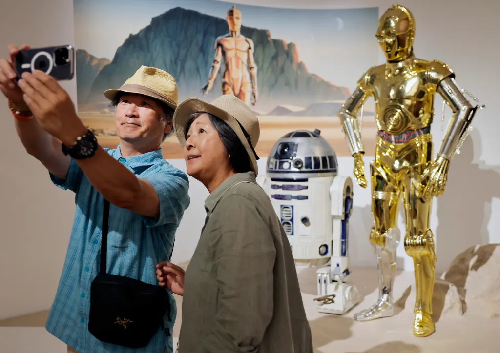 Visitors take a selfie with the R2-D2 and C-3PO figures in the 