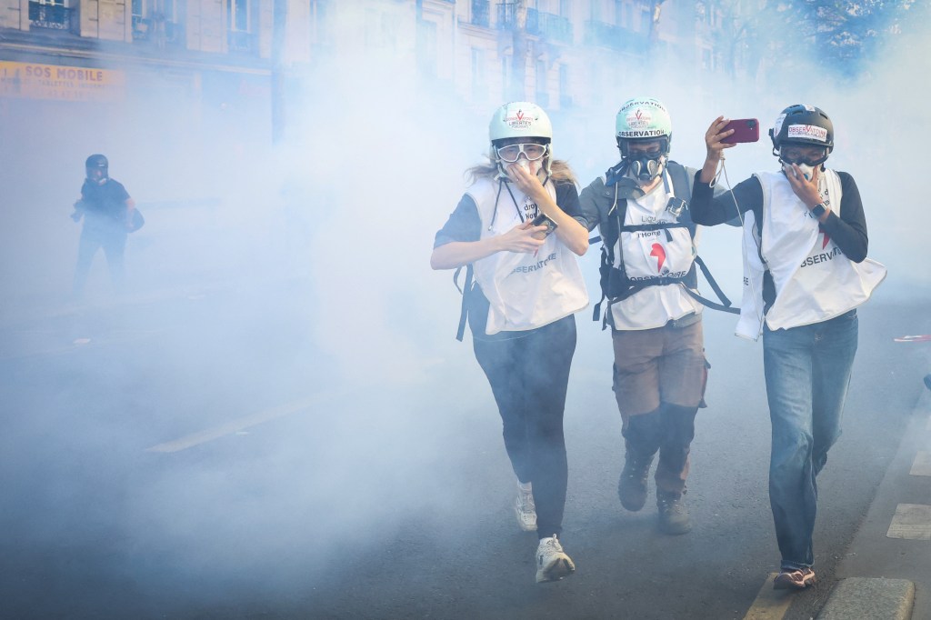 Observers from the Human Rights League run through smoke during a high-school student demonstration in Paris.