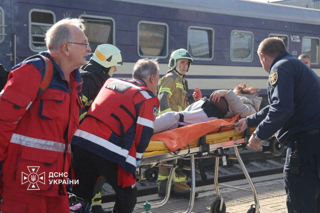 Emergency workers carry an injured person on a stretcher at a railway station in Dnipro following a drone strike.